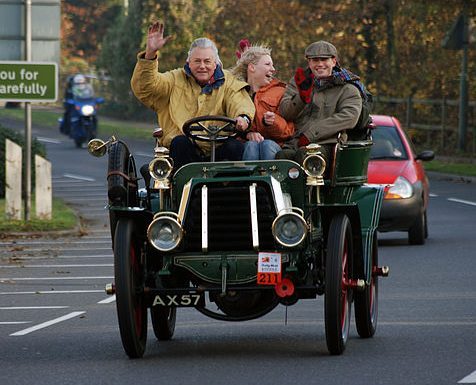 Onnellisia ihmisiä vanhanaikaisen auton kyydissä.