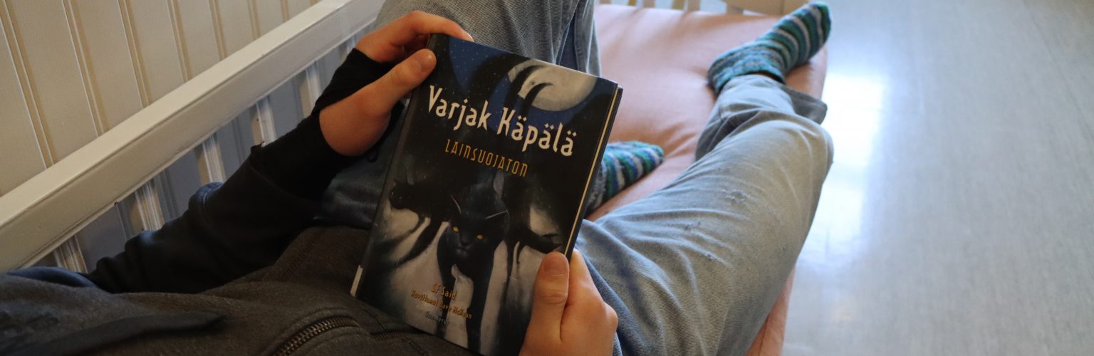 Varjak Käpälä -kirja lukijan sylissä